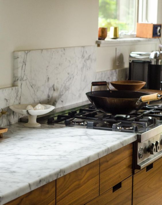Various kinds of marble countertops in a kitchen with wooden cabinets and a gas stove.