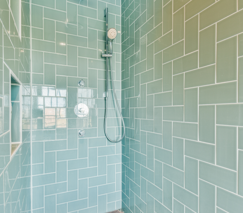 Fresh and airy shower space with glossy aqua blue subway tiles reflecting the light, creating a calming and clean atmosphere.