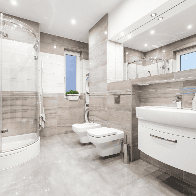 Modern bathroom with beige tiles, glass shower, and white fixtures including a bidet and floating vanity