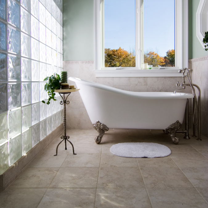 Classic clawfoot bathtub in a bright, vintage-style bathroom with large windows and glass block wall, showcasing types of bathtubs