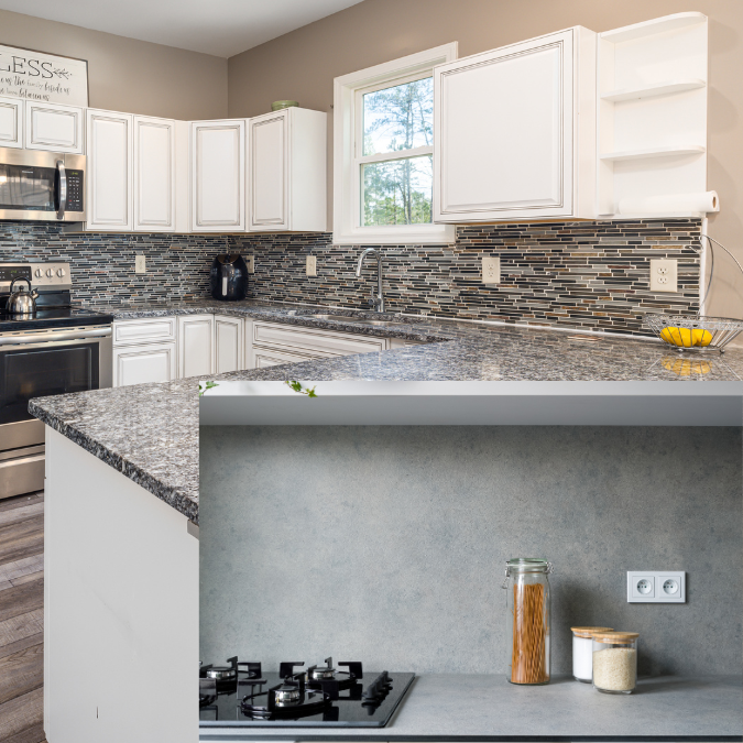 Kitchen with gray countertops featuring a mosaic tile backsplash and a minimalist design with smooth gray finishes.